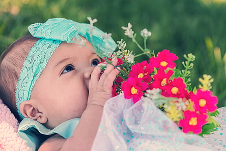 baby in white and blue dress holding flower bouquet thumbnail