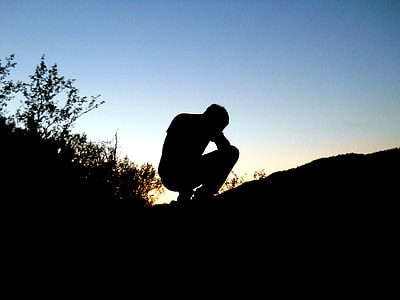 silhouette of man sitting near grass during daytime thumbnail