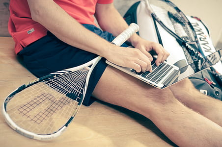 person sitting on the floor with laptop and racquetball racket on his lap thumbnail
