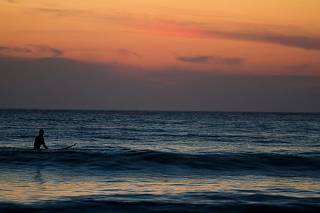 silhouette of person in body of water during golden hour thumbnail
