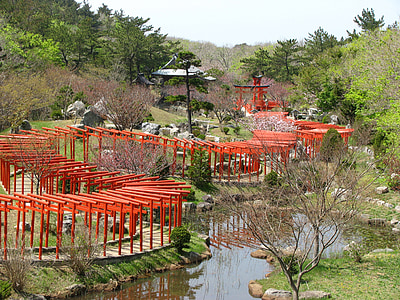 red wooden pathway to gazebo beside body of water at daytime thumbnail