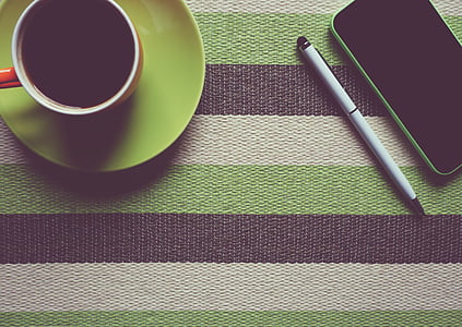 flat-lay photography of teacup beside iPhone and pen on striped table thumbnail