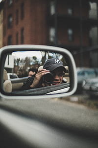 selective focus photography of vehicle side mirror with person taking photo using DSLR camera thumbnail