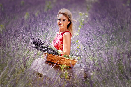 woman in red lace sleeveless top carrying basket full of purple petaled flowers thumbnail
