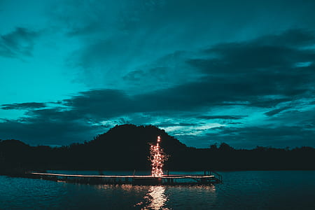 light on dock near ocean and mountain during night time thumbnail