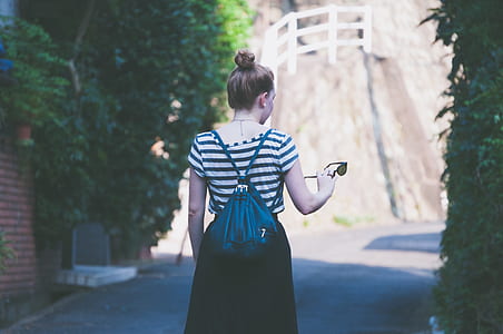 woman holding sunglasses standing on road during daytime thumbnail