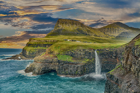 green and brown mountain with waterfalls over water under cloudy sky thumbnail