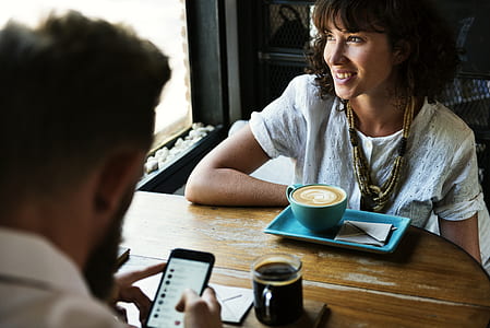 man using phone sitting in front of woman thumbnail