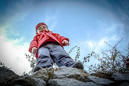 boy wearing gray pants standing on rock boulder thumbnail