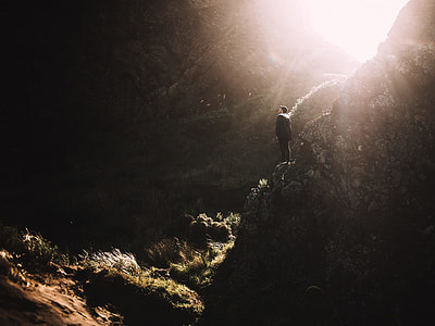 man standing on mountain against light at daytime thumbnail