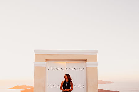 Woman Wearing Black Sleeveless Top Posing in Front of White Wooden Door thumbnail