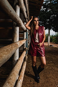 Woman Wearing Maroon Leather Sleeveless Jacket Beside Horse Stable thumbnail