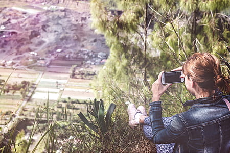 Woman Holding Smartphone Overlooking Plain Field thumbnail