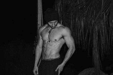 grayscale photo of topless man wearing black knit hat thumbnail