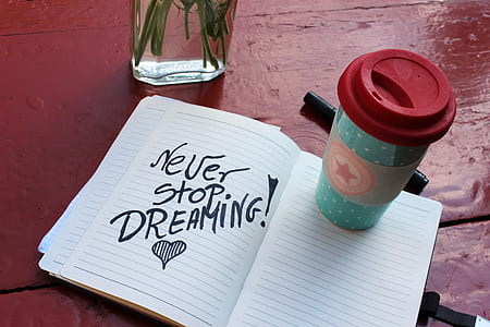teal and white plastic drinking cup with lid on notebook near glass bottle thumbnail