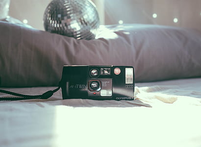 black Olympus film camera near mirror ball on bed thumbnail