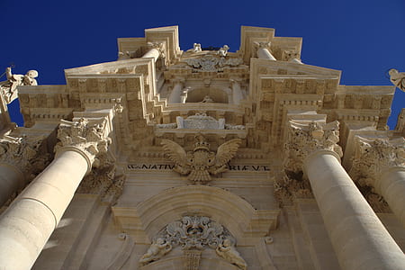 low angle photography of brown concrete building under blue sky thumbnail