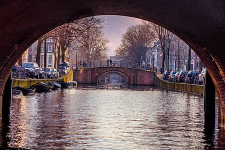 canal with brown arch bridge during daytime thumbnail