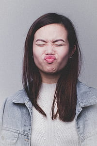 woman in gray denim jacket and white top making face thumbnail