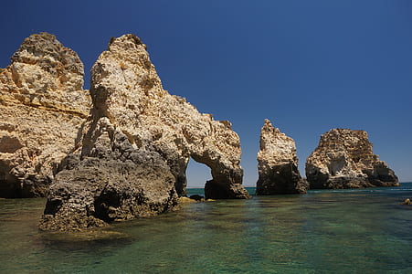 rock formation on beach under blue sky thumbnail