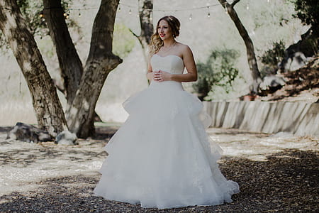 woman in white strapless wedding gown walking on black soil thumbnail