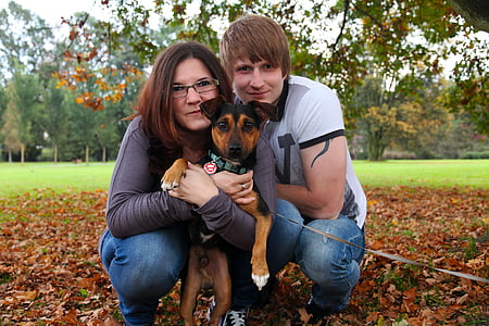 woman holding dog beside man during daytime thumbnail