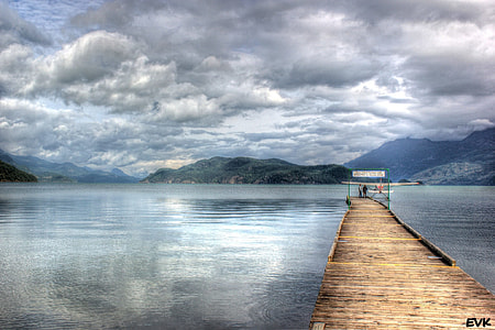 wooden dock on body of water under cloudy sky thumbnail