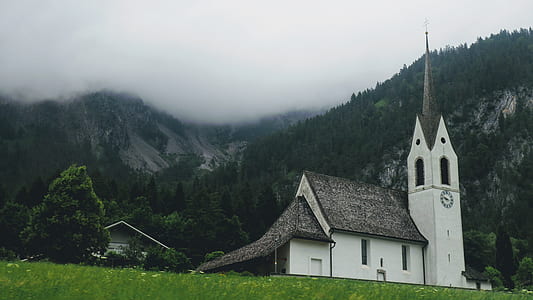 white and gray concrete building on green grass under gray sky thumbnail