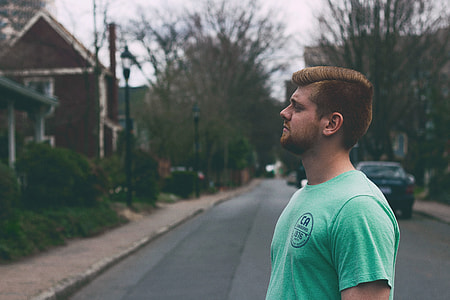 man wearing teal shirt stood in the middle of the street looking on his other side thumbnail