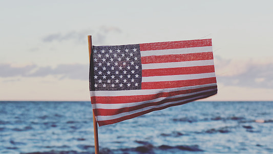 flag of America near ocean under cloudy sky thumbnail