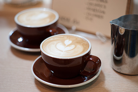 brown ceramic mug filled with latte on brown wooden surface thumbnail