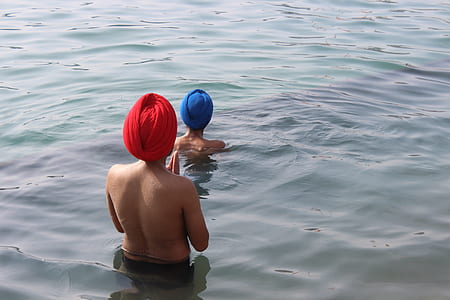 two woman taking bath on calm water at daytime thumbnail