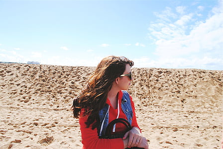 woman on beige field wearing sunglasses and red hoodie looking upside thumbnail