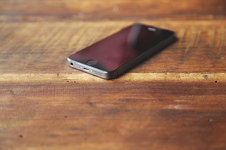 turned-off space gray iPhone 5s on brown wooden surface thumbnail