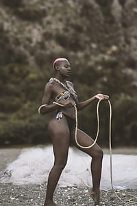 woman wearing brown, white, and black bikini holding rope of fish net selective focus photography thumbnail