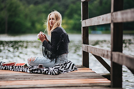 Blonde woman having a healthy snack at the wooden pier thumbnail