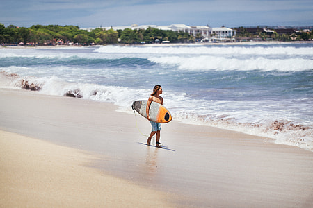 surfer looking at the waves beside shore thumbnail
