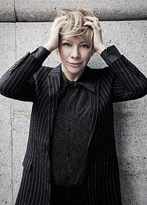 woman wearing black and white striped suit with hands on head thumbnail