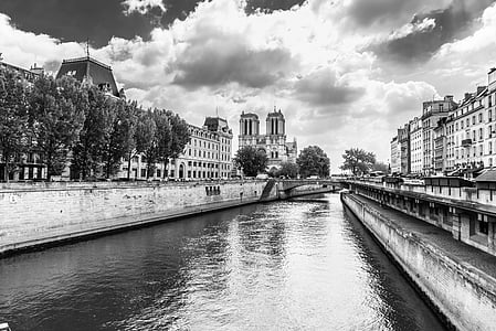 grayscale photography of body of water near between buildings thumbnail