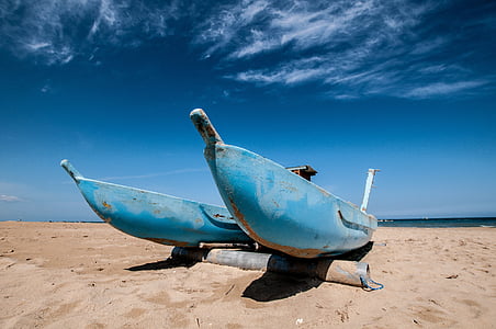 blue-and-white sail boat on beach shore during daytime thumbnail