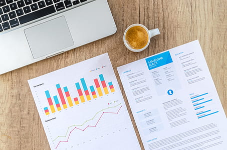 two printed paper beside mug and laptop thumbnail