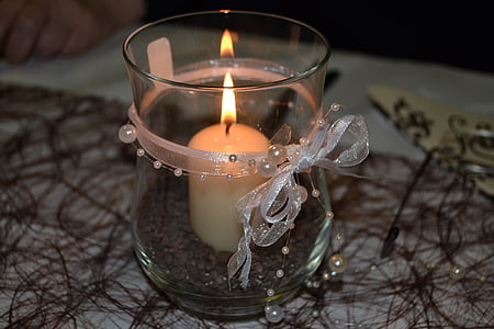 lighted white candle in clear glass vase thumbnail