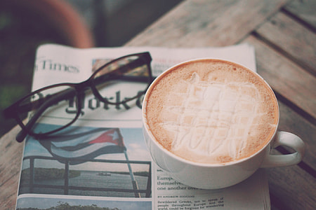 white coffee cup on top of newspaper near on black framed eyeglasses thumbnail