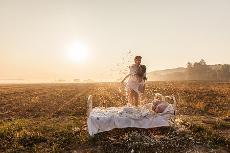 man and woman in front of bed on field during daytime thumbnail