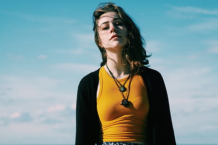 woman in black cardigan and brown tank top standing under blue sky thumbnail