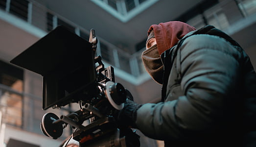 person wearing black mask holding camera stand thumbnail