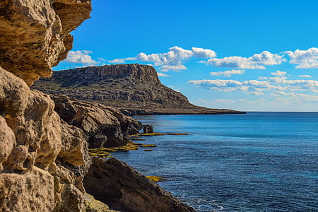 brown cliff and calm body of water under blue at daytime thumbnail