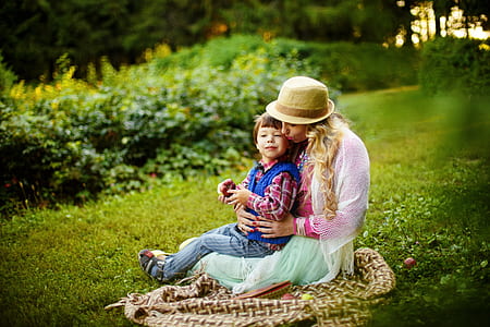 selective focus of woman sitting beside boy on picnic blanket thumbnail