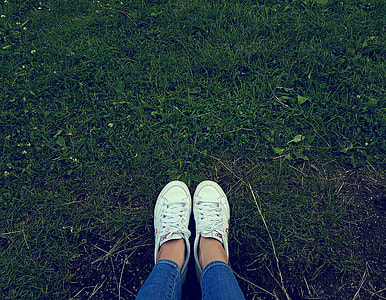 person wearing white low-top sneakers  standing on green grass thumbnail