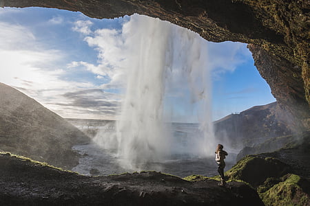 woman taking a photo inside Skogafoss falls thumbnail